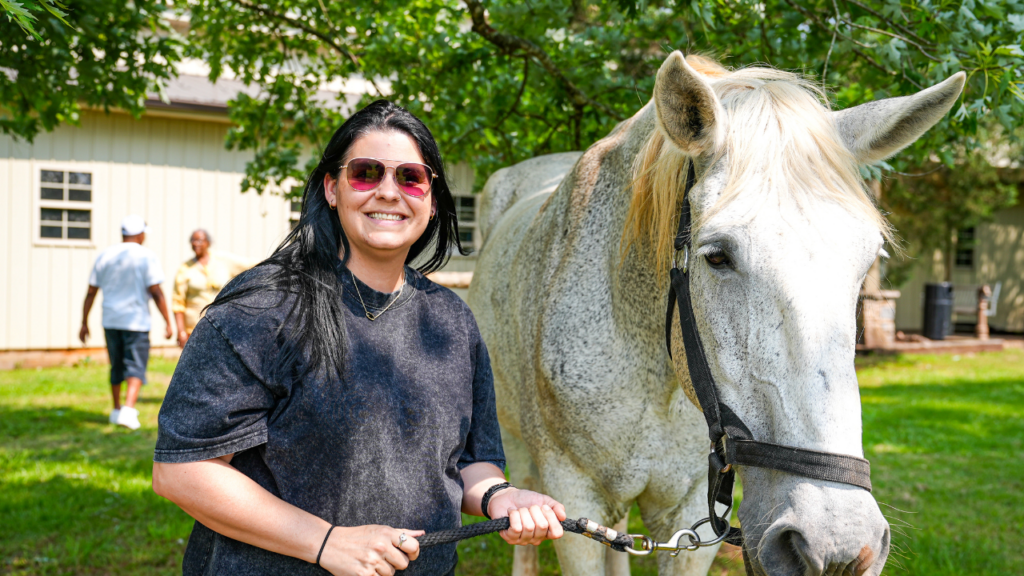 One of JourneyPure's alumni posing with one of the therapy horses