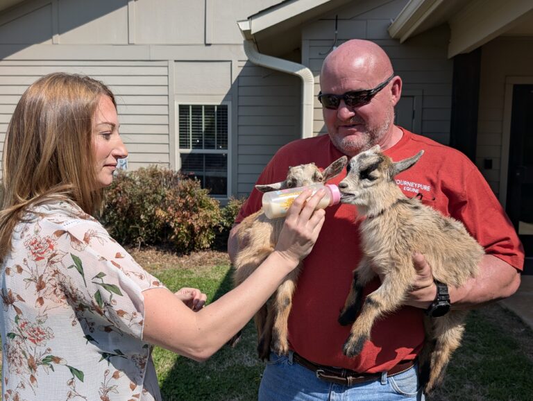 JourneyPure at The River Executive Director Jamie Bercich feeds baby goat Bonnie held by equine facilitator Jon Levi.